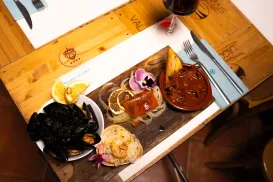 A wooden table with a seafood platter and a glass of red wine.