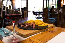 Steak and fries with red wine on a restaurant table.