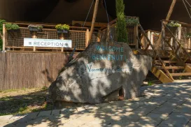 Rock with welcoming text in front of a wooden reception area.