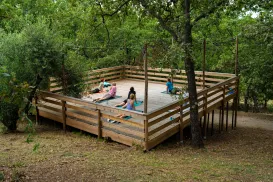 Yoga session on a wooden platform surrounded by trees.