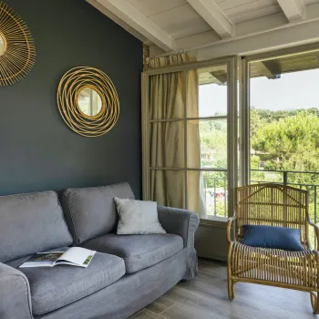Cozy living room with gray sofa, wicker chair, and sunny balcony view.