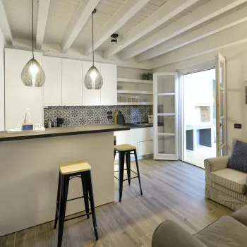 Cozy kitchen with bar stools, open shelves, and a living area with sofas.