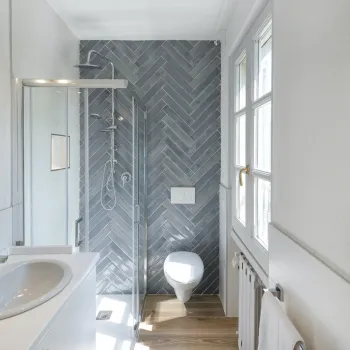 Bathroom with a sink, mirror, and herringbone tiled shower.