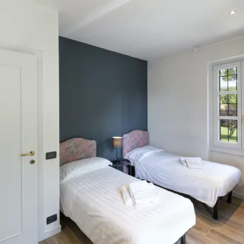 Two neatly made twin beds in a bright room with a window.