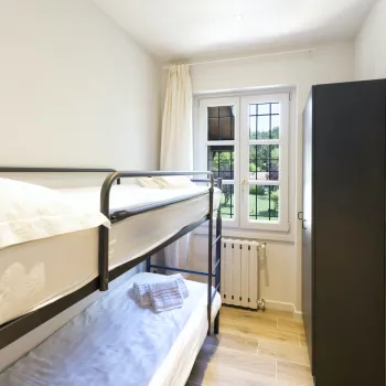 Bunk beds in a small, bright room with a window and a colorful wall poster.