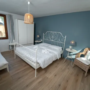 Cozy bedroom with blue accent wall, iron bed, wicker chair, and wooden floor.