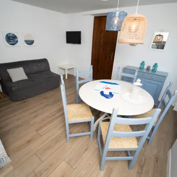 Compact living room with blue chairs, round table, and wall art.