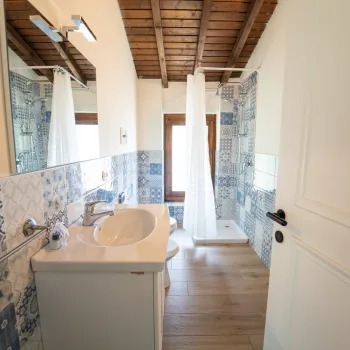 Spacious bathroom with wooden ceiling, blue tile accents, and a white sink.