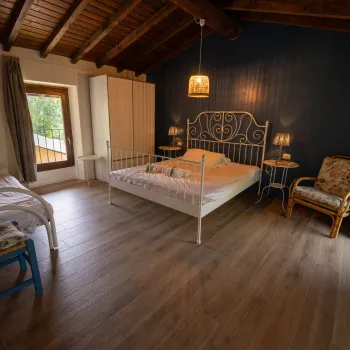 Cozy bedroom with wooden ceiling, two beds, and a window with a view.