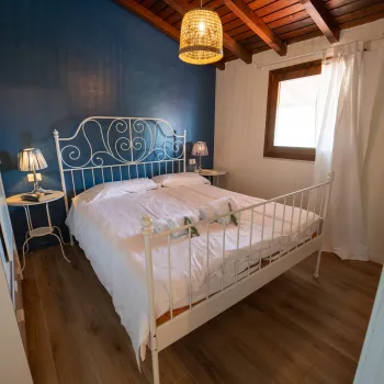 Cozy bedroom with blue walls, white bed, and warm lighting.