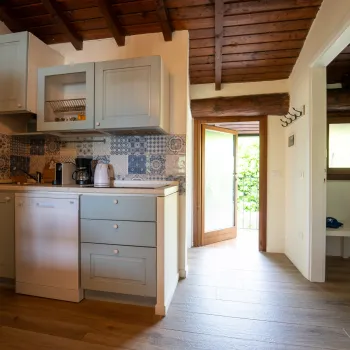 Cozy kitchen with wooden ceiling and open door to greenery.