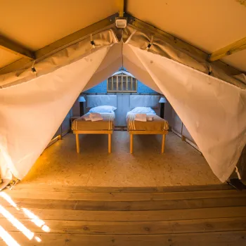 Cozy tent interior with two neatly made beds.
