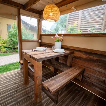 Cozy patio with a wooden table and benches, under a wicker lamp.