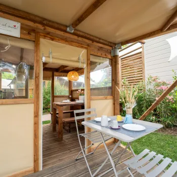 Cozy cabin patio with a table set for breakfast, under a tan canopy.