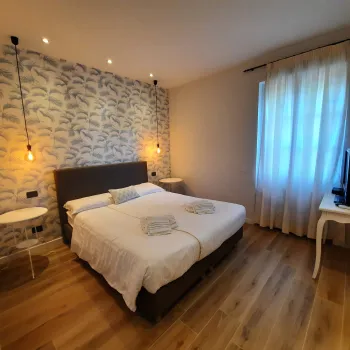 Cozy bedroom with patterned wall, double bed, and soft lighting.