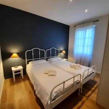 Twin beds in a tidy, softly lit room with a dark accent wall.