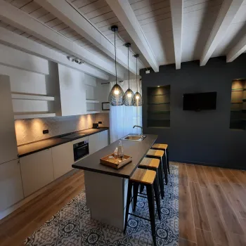 Modern kitchen with island, stools, pendant lights, and wood beams.
