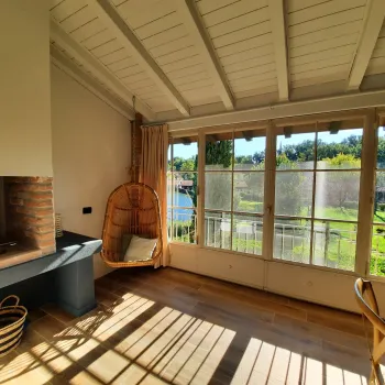 Sunlit room with large windows, wooden floors, and a hanging chair.