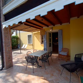 Covered patio with a dining set, wicker chairs, and yellow walls.