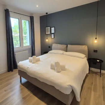 Modern bedroom with a double bed, dark accent wall, and hanging lights.