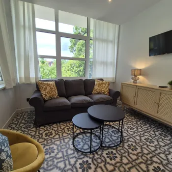 Cozy living room with a sofa, patterned rug, and round tables.