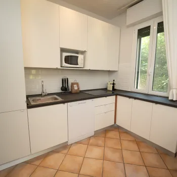 White kitchen with corner cabinets, tile floor, window, and countertop appliances.