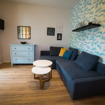 Cozy living room with blue sofas, floral wall, and small round tables.