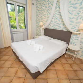Cozy bedroom with a double bed, white linens, and floral wallpaper.