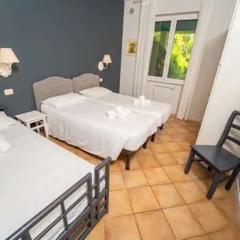 Two single beds in a bright room, folded towels, window view of greenery.