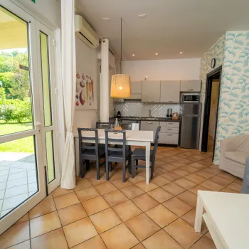 Sunny kitchen and living area with tiled floor, dining table, and sofa.