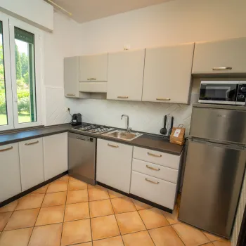Small modern kitchen with cream cabinets, tiled floor, and stainless steel appliances.
