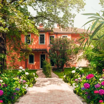 Orange house with a garden path and vibrant pink flowers.
