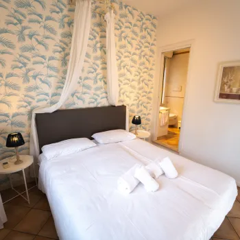 Cozy bedroom with white bedding, patterned wallpaper, and soft lighting.