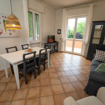 Bright living-dining room with table, chairs, sofa, and large windows.