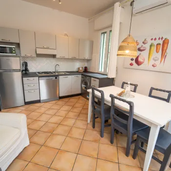 Modern kitchen with white cabinets, dining table, and tile floor.