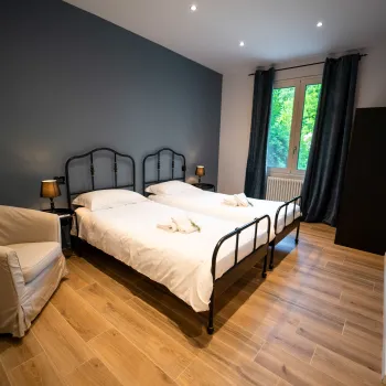 Two twin beds in a modern room with wood floors and a window.