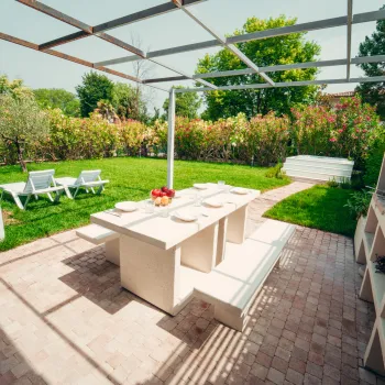 Sunlit patio with table, chairs, and garden view.