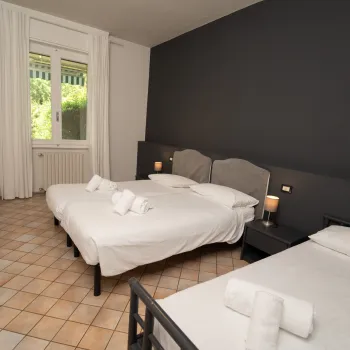 Two beds in a hotel room with a window and tiled floor.