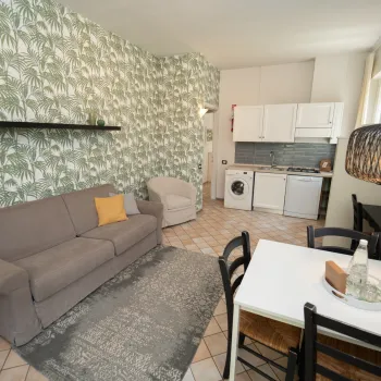 Cozy living room with a gray sofa, dining table, and green leafy wallpaper.