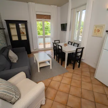 Cozy living room with a sofa, armchair, dining table, and large windows.