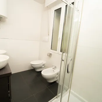 Modern bathroom with two sinks, a bidet, and a shower.