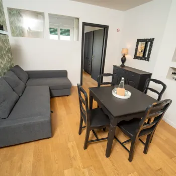 Living room with gray sofa, black dining table, and wall-mounted TV.