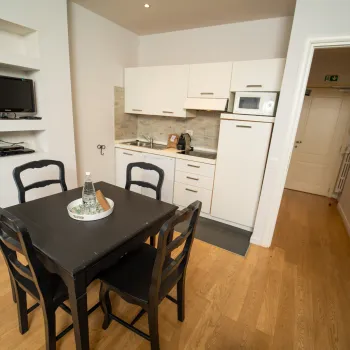 Compact kitchen with black dining table and four chairs.