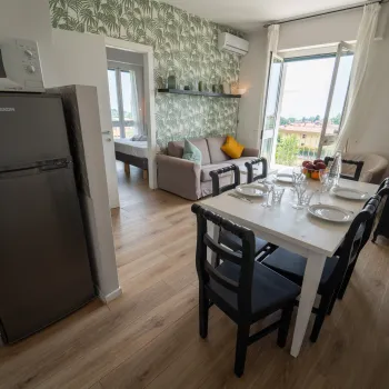 Apartment dining area with table set for four, kitchen and living room visible.