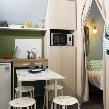 Cozy kitchenette with table, chairs, microwave, and a curtained-off bed area.