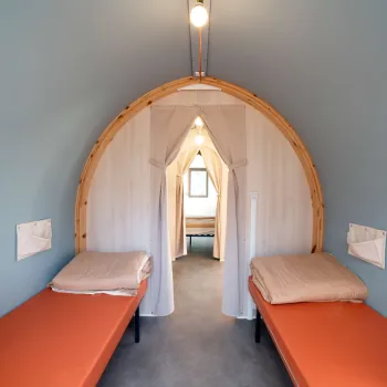 Cozy cabin interior with two single beds and a small window.