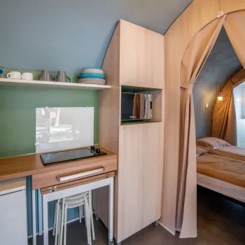 Compact kitchenette with a small dining area and a cozy bedroom behind a curtain.