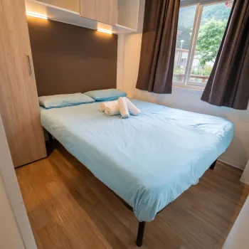 Neatly made bed with blue sheets and towel swans in a cozy room.