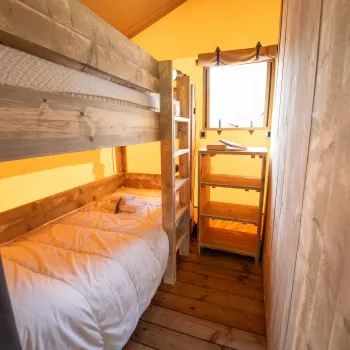 Cozy cabin room with wooden bunk beds, warm lighting, and a small window.