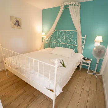Cozy bedroom with white bed, teal accent wall, and soft lighting.